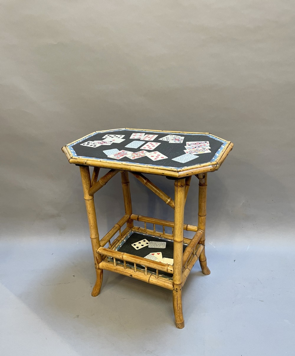 A late nineteenth-century Victorian bamboo occasional table featuring a two-tier structure with decoupage playing cards under varnish on the surfaces.