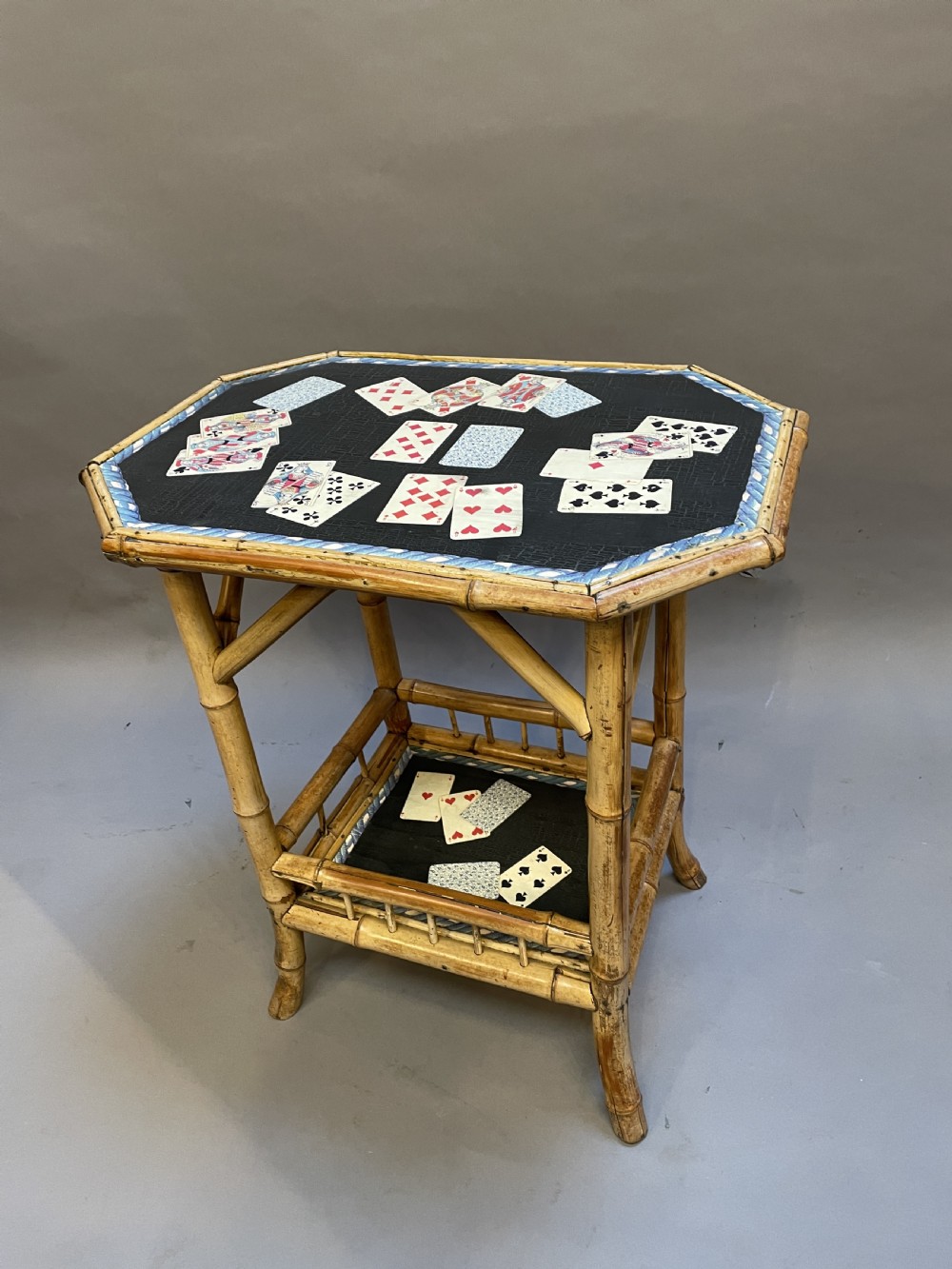 A late nineteenth-century Victorian bamboo occasional table featuring a two-tier structure with decoupage playing cards under varnish on the surfaces. View V