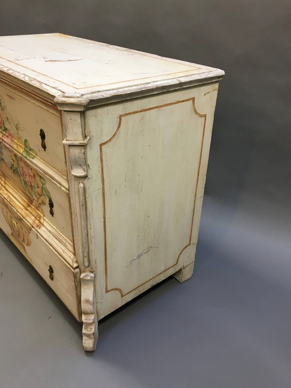 A 19th-century cream painted chest of drawers featuring three long drawers decorated with a central hand-painted motif of a floral urn. View II