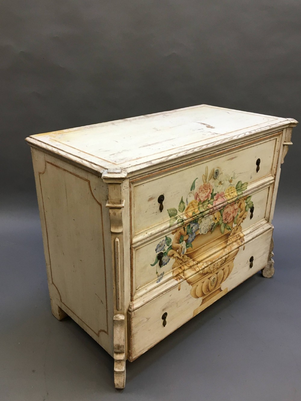 A 19th-century cream painted chest of drawers featuring three long drawers decorated with a central hand-painted motif of a floral urn. View VIII