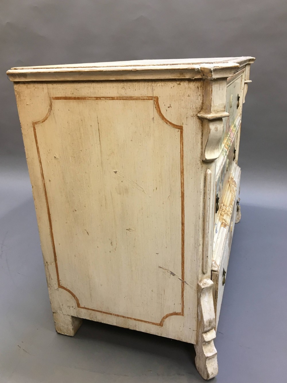 A 19th-century cream painted chest of drawers featuring three long drawers decorated with a central hand-painted motif of a floral urn. View X