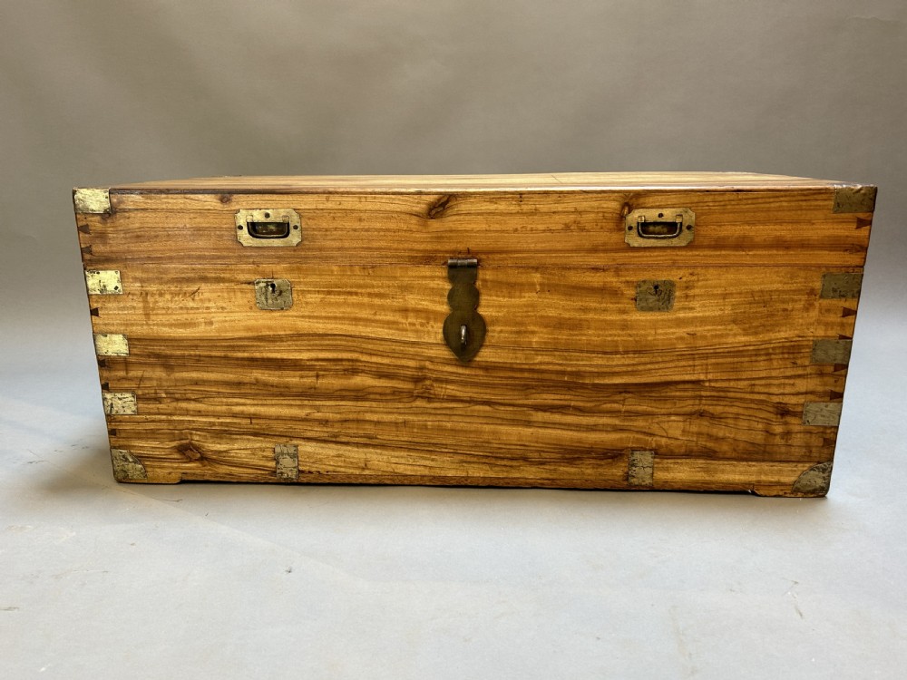 An antique rectangular camphor wood campaign trunk with flush metal handles, corner brackets, exposed dovetail joinery, and a central latch. View III