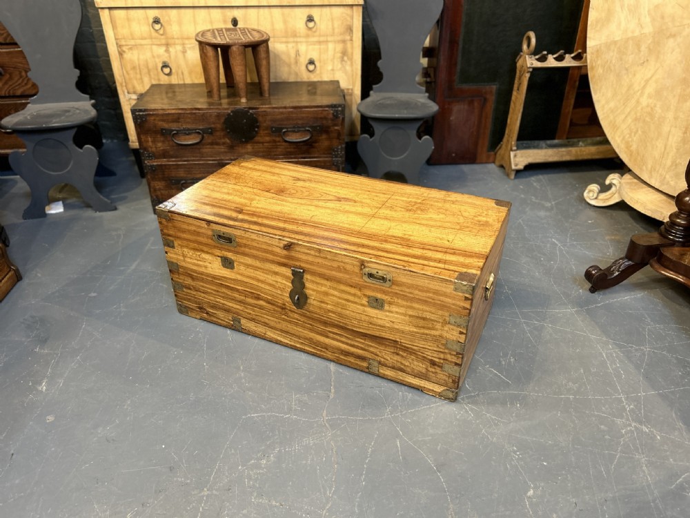 An antique rectangular camphor wood campaign trunk with flush metal handles, corner brackets, exposed dovetail joinery, and a central latch. View X
