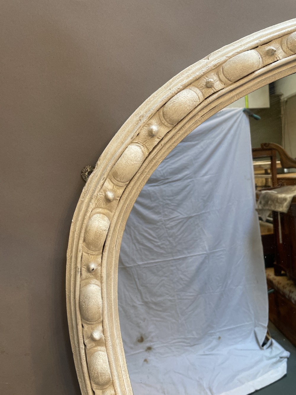 A 19th-century arched overmantel mirror featuring an off-white painted frame decorated with beaded moulding and small projecting feet. View V