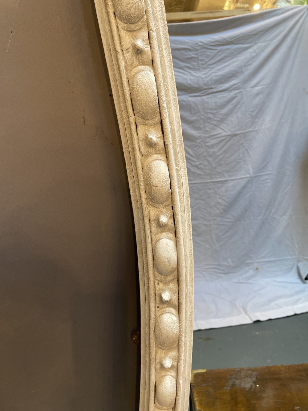A 19th-century arched overmantel mirror featuring an off-white painted frame decorated with beaded moulding and small projecting feet. View VI