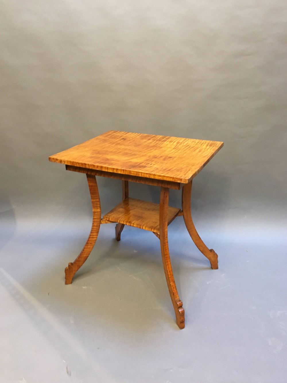 An Art Deco golden Karelian birch side table featuring a square top, lower tier shelf, and flared outward curved legs. View II