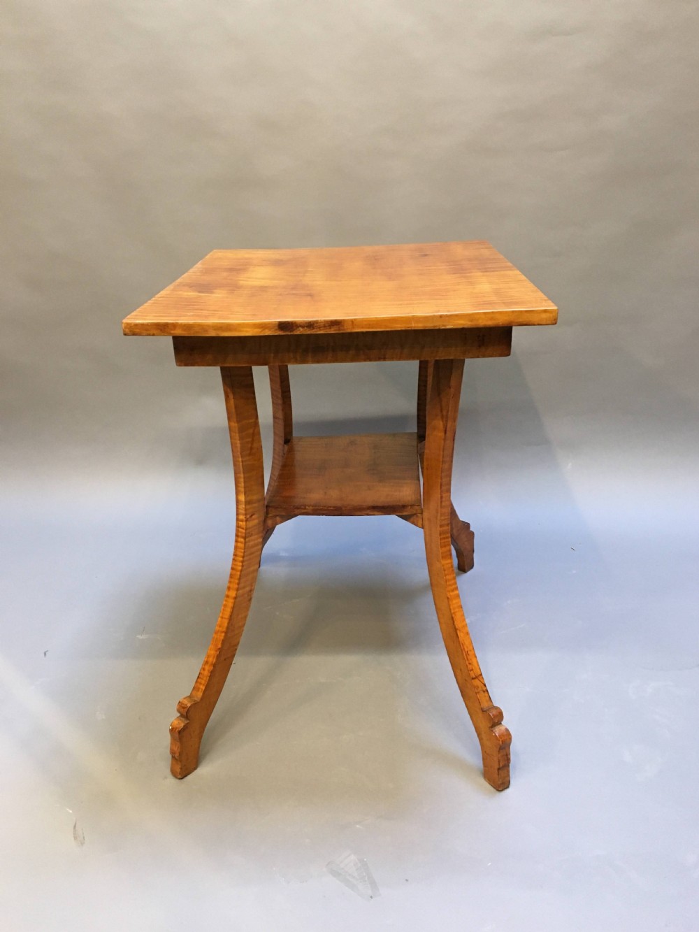 An Art Deco golden Karelian birch side table featuring a square top, lower tier shelf, and flared outward curved legs. View V