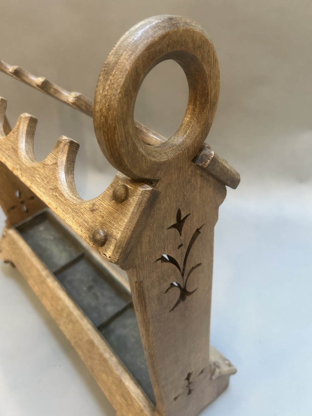 An antique oak umbrella and stick stand featuring a scalloped upper rail, carved ring handles, inlaid side uprights, and a metal drip tray at the base. View III