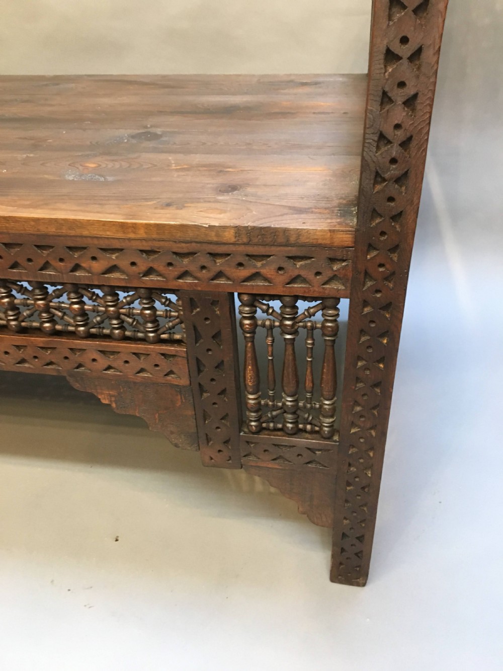A dark brown carved wooden window seat featuring raised curved arms and geometric mashrabiya lattice panels along the base. View IV