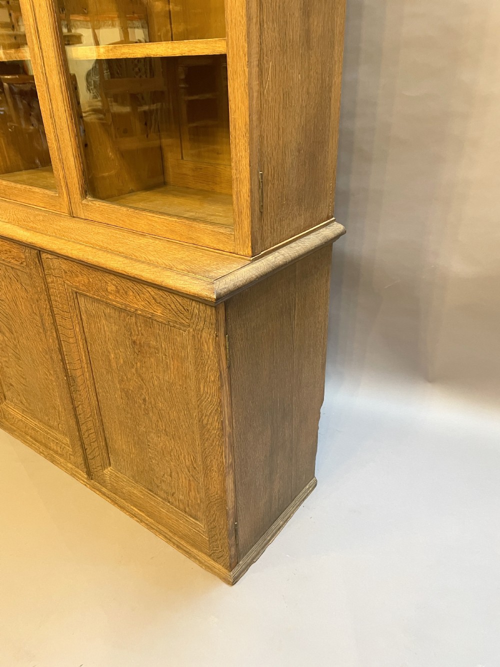 A tall Victorian light oak two-part bookcase with two upper glazed doors revealing adjustable shelves and a two-door cupboard base. View II