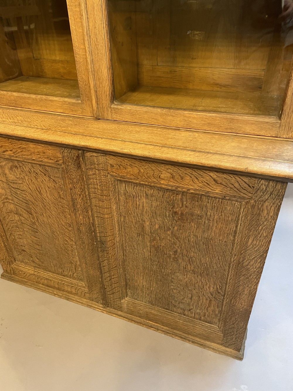 A tall Victorian light oak two-part bookcase with two upper glazed doors revealing adjustable shelves and a two-door cupboard base. View III