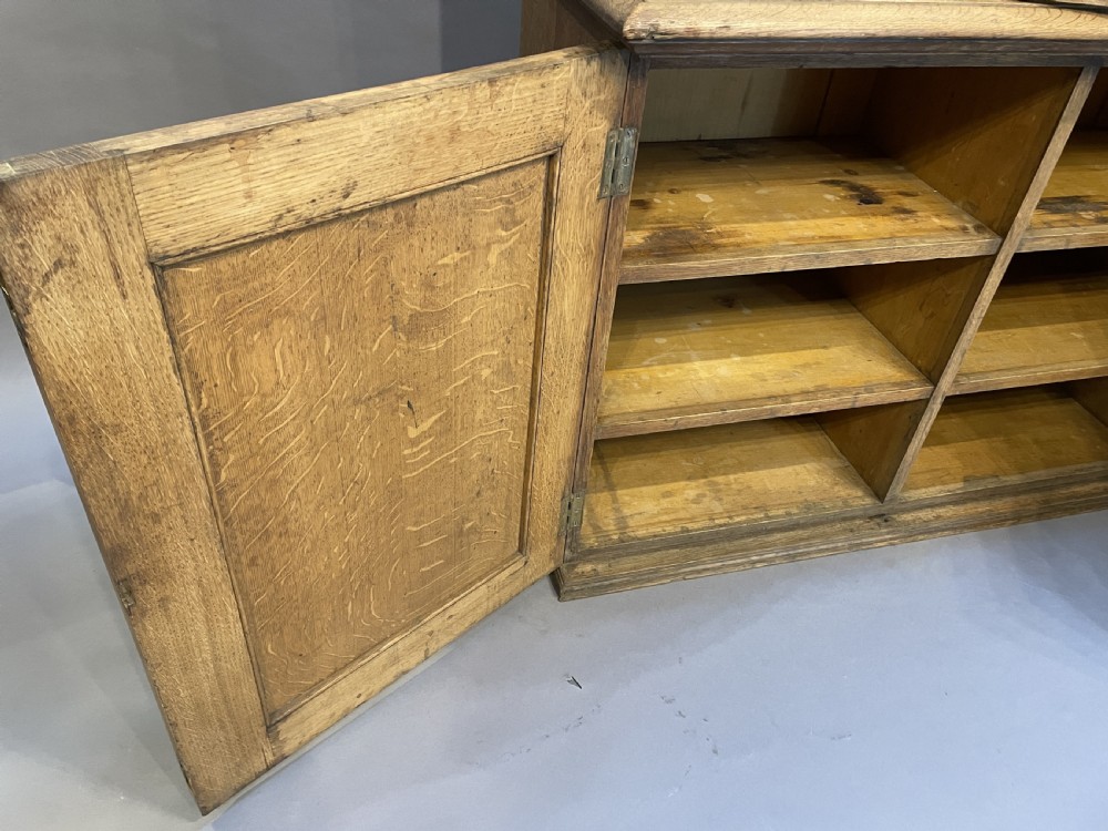 A tall Victorian light oak two-part bookcase with two upper glazed doors revealing adjustable shelves and a two-door cupboard base. View VI