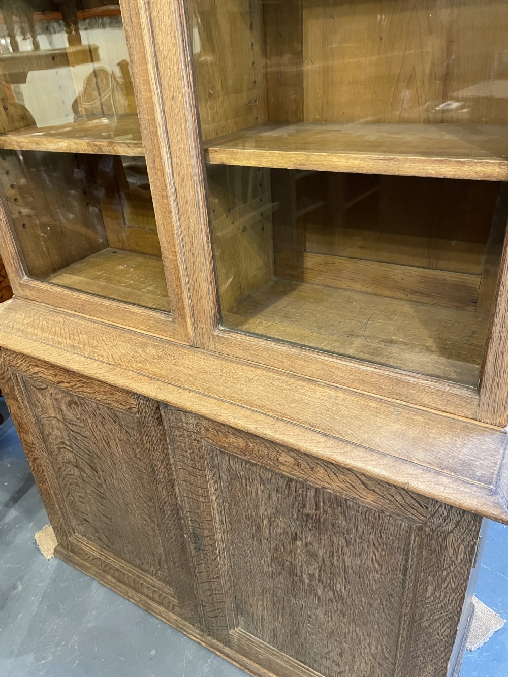 A tall Victorian light oak two-part bookcase with two upper glazed doors revealing adjustable shelves and a two-door cupboard base. View XII