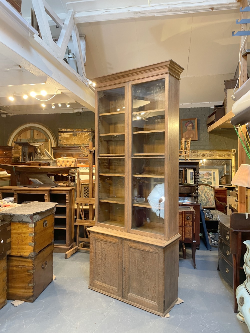A tall Victorian light oak two-part bookcase with two upper glazed doors revealing adjustable shelves and a two-door cupboard base. View XIII