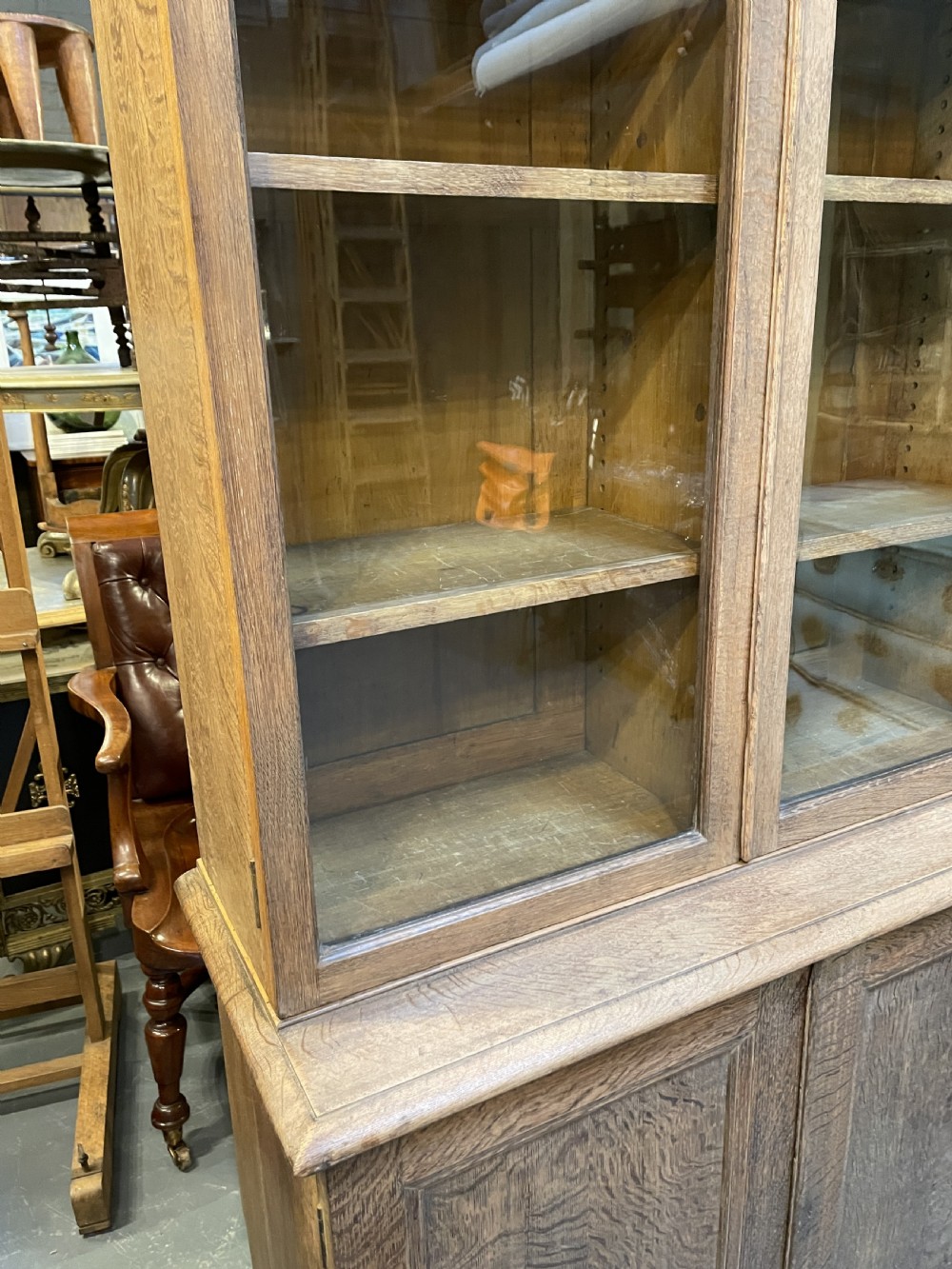 A tall Victorian light oak two-part bookcase with two upper glazed doors revealing adjustable shelves and a two-door cupboard base. View XXI