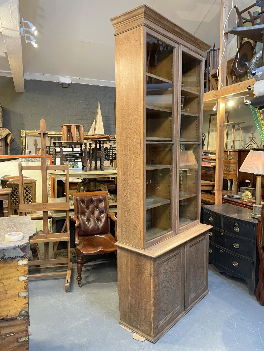 A tall Victorian light oak two-part bookcase with two upper glazed doors revealing adjustable shelves and a two-door cupboard base. View XXII