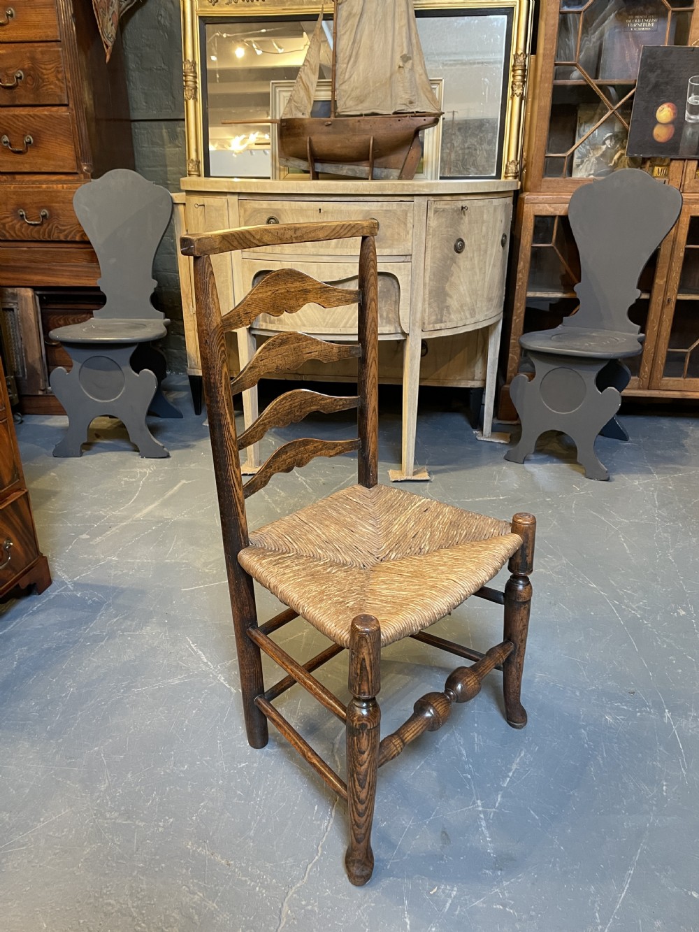 A wooden country side chair featuring a ladderback with four wavy horizontal slats, turned front legs, and a woven rush seat. View VIII