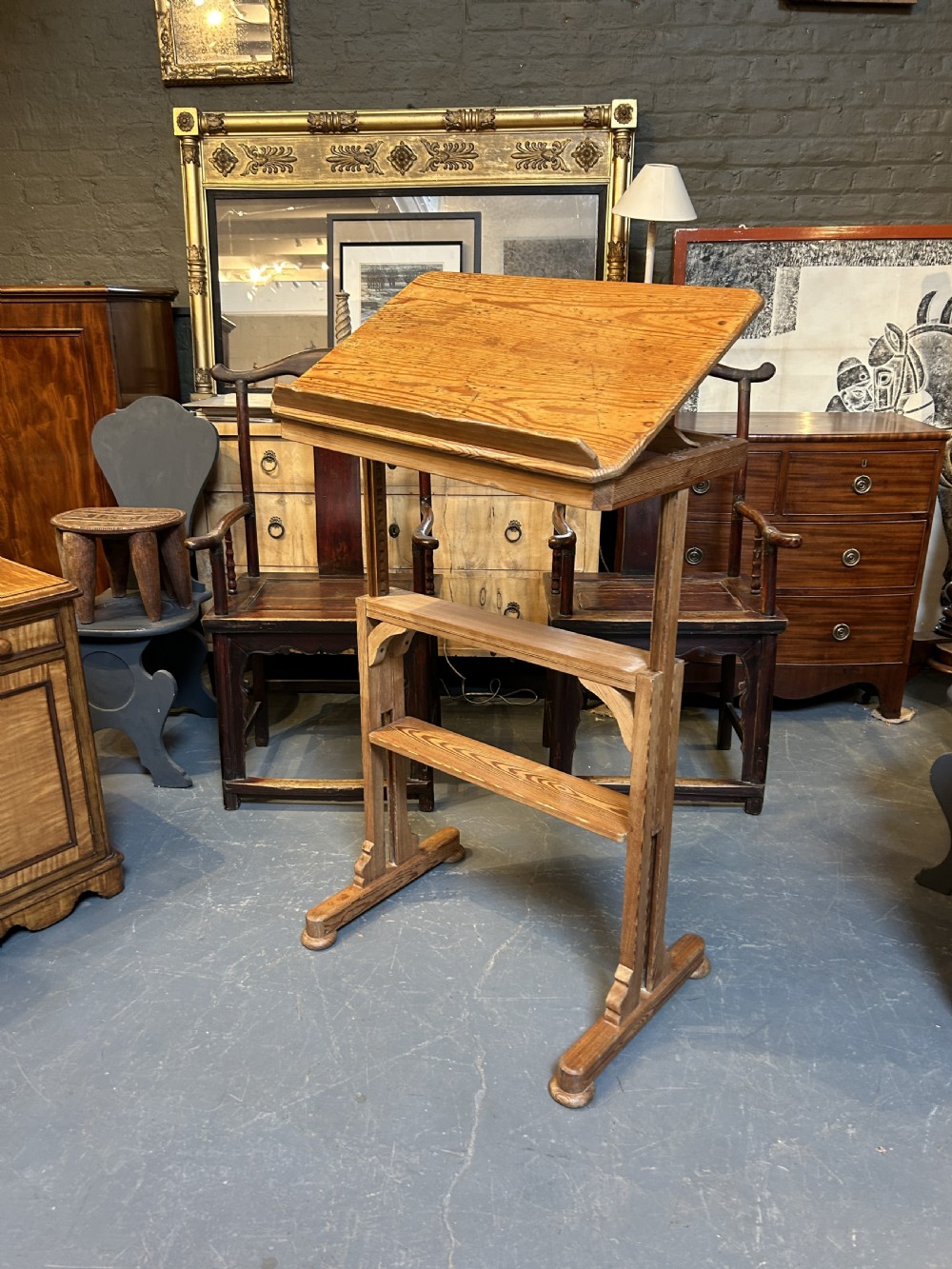 An early twentieth-century pine lectern table featuring a slanted reading surface with a retaining lip, supported by a trestle base with a lower shelf. View V
