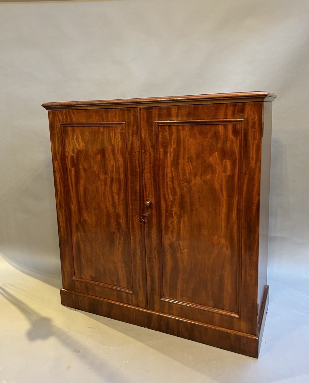 A 19th-century Victorian mahogany linen press cupboard featuring flame mahogany door panels resting on a solid plinth base.