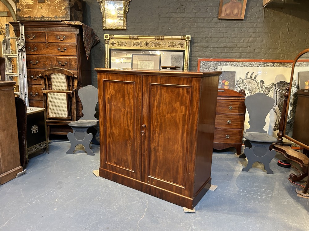 A 19th-century Victorian mahogany linen press cupboard featuring flame mahogany door panels resting on a solid plinth base. View II