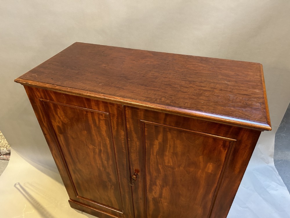 A 19th-century Victorian mahogany linen press cupboard featuring flame mahogany door panels resting on a solid plinth base. View V