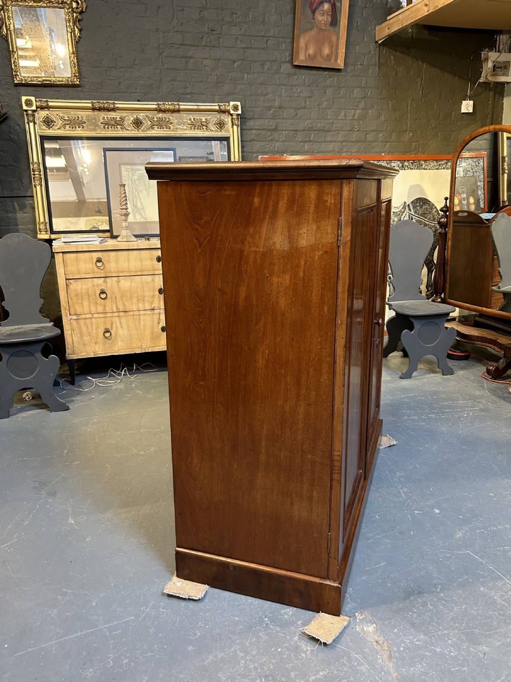 A 19th-century Victorian mahogany linen press cupboard featuring flame mahogany door panels resting on a solid plinth base. View VI