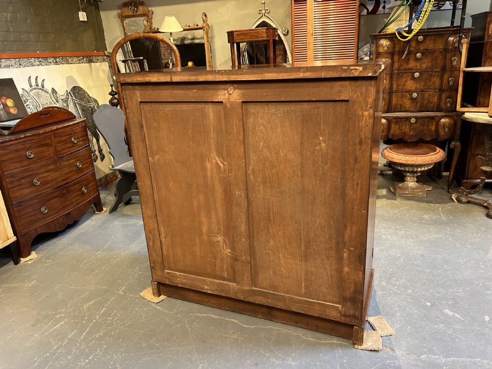 A 19th-century Victorian mahogany linen press cupboard featuring flame mahogany door panels resting on a solid plinth base. View VII