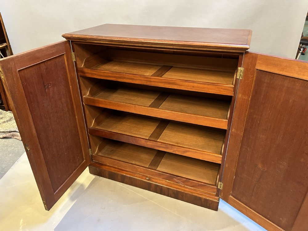A 19th-century Victorian mahogany linen press cupboard featuring flame mahogany door panels resting on a solid plinth base. View IX