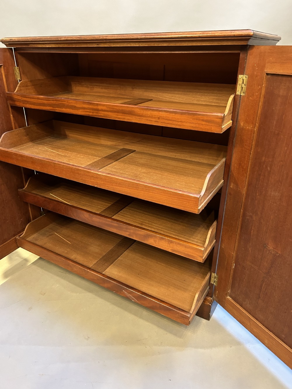 A 19th-century Victorian mahogany linen press cupboard featuring flame mahogany door panels resting on a solid plinth base. View X