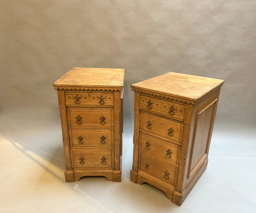 A pair of light oak four-drawer bedside chests featuring carved top edge details and brass drop handles.