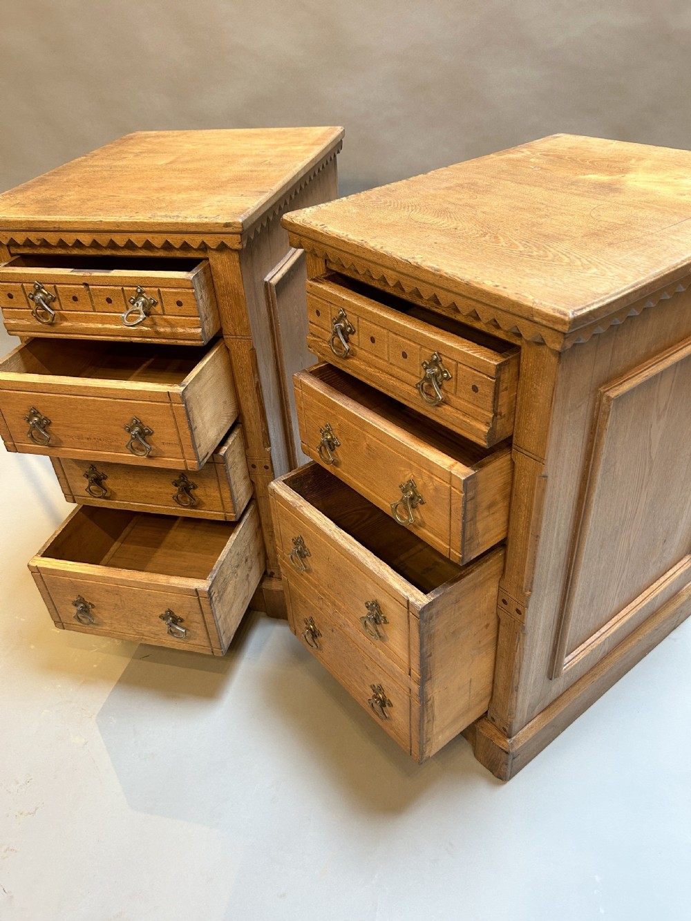 A pair of light oak four-drawer bedside chests featuring carved top edge details and brass drop handles. View VI