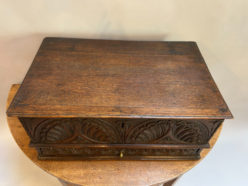 An eighteenth-century dark oak bible box featuring relief carved lunettes, a brass teardrop drawer pull, and a hinged lid. View II