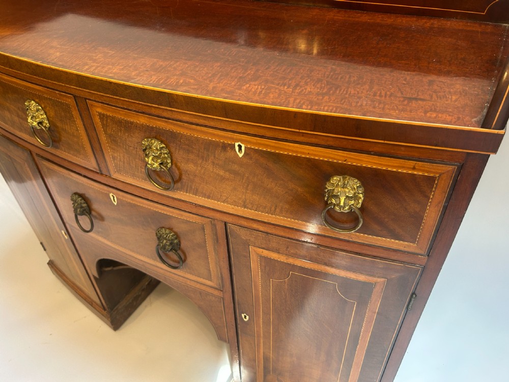A George IV mahogany sideboard featuring a gallery back, geometric wood inlay, brass lion-mask handles, and pedestal cupboards flanking a central drawer. View II