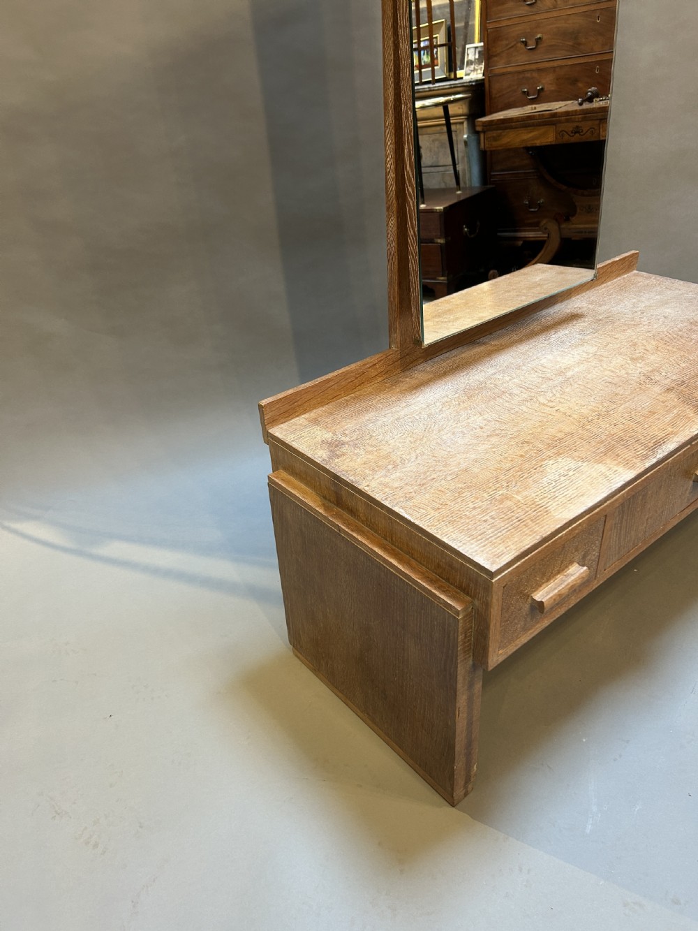 An Art Deco light oak dressing chest featuring three frieze drawers with wooden block handles and a tall rectangular mirror. View III