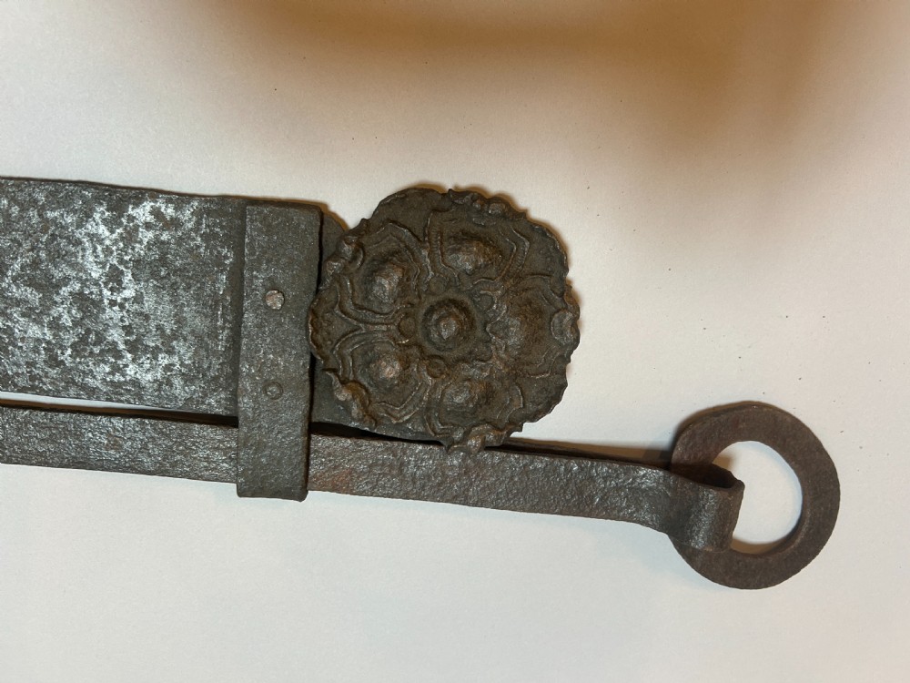 An 18th-century hand-forged wrought iron adjustable chimney crane featuring a sawtooth trammel mechanism, scrolled ends, and a decorative rosette. View II