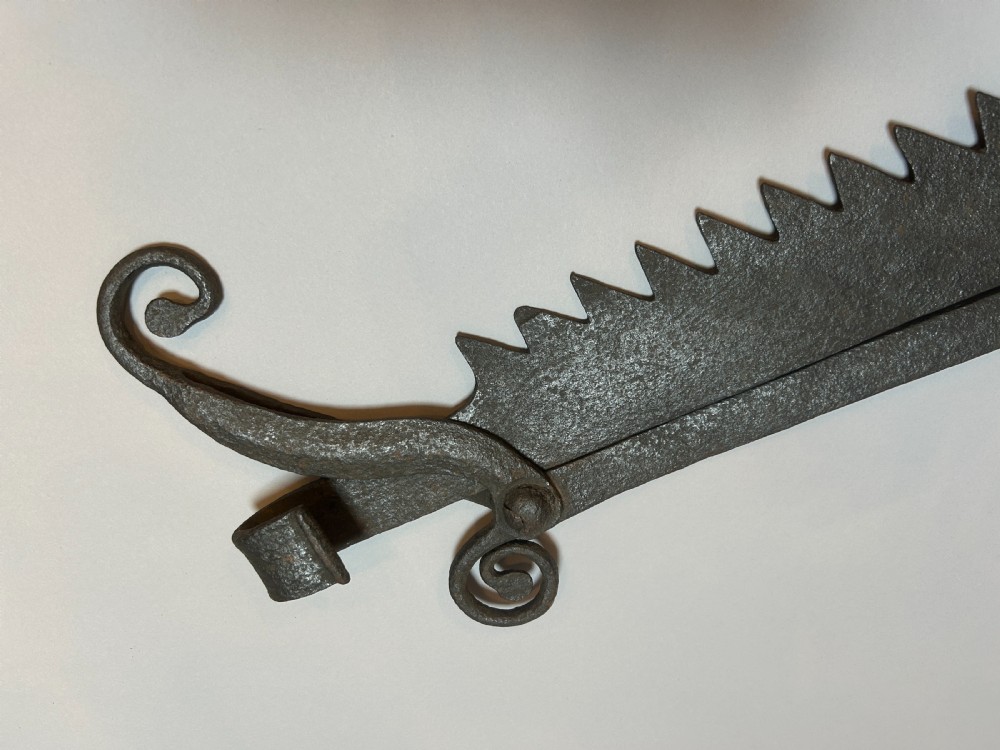 An 18th-century hand-forged wrought iron adjustable chimney crane featuring a sawtooth trammel mechanism, scrolled ends, and a decorative rosette. View V