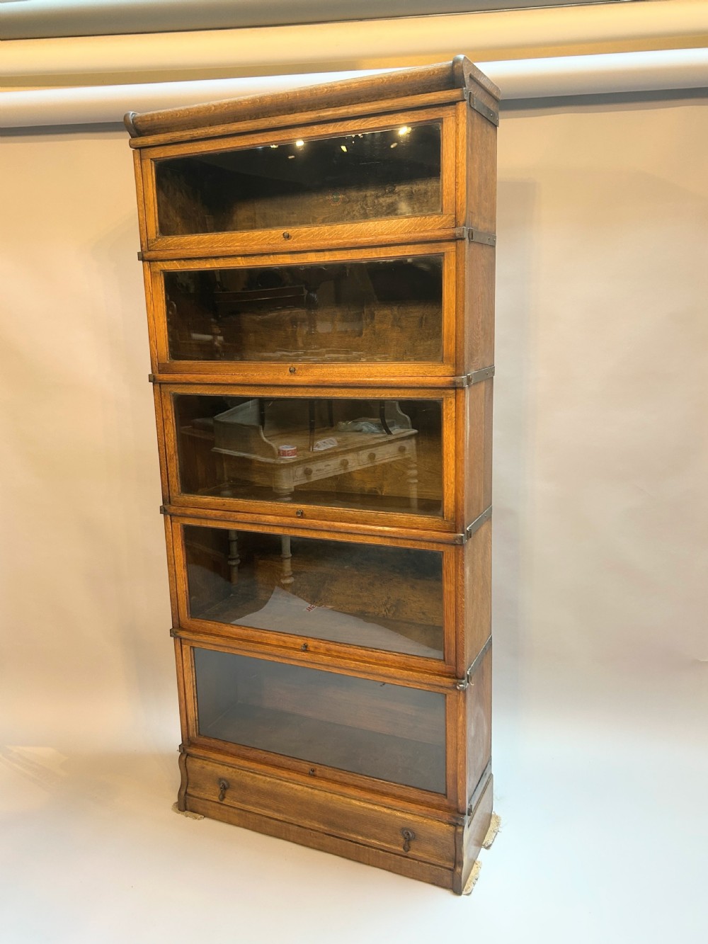 A tall five-tier oak Globe Wernicke stacking bookcase with glazed up-and-over doors and a base drawer.