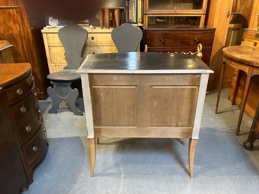A French Art Deco black ebonised side cabinet with fluted doors, brass key hardware, and tapered light-coloured legs. View X