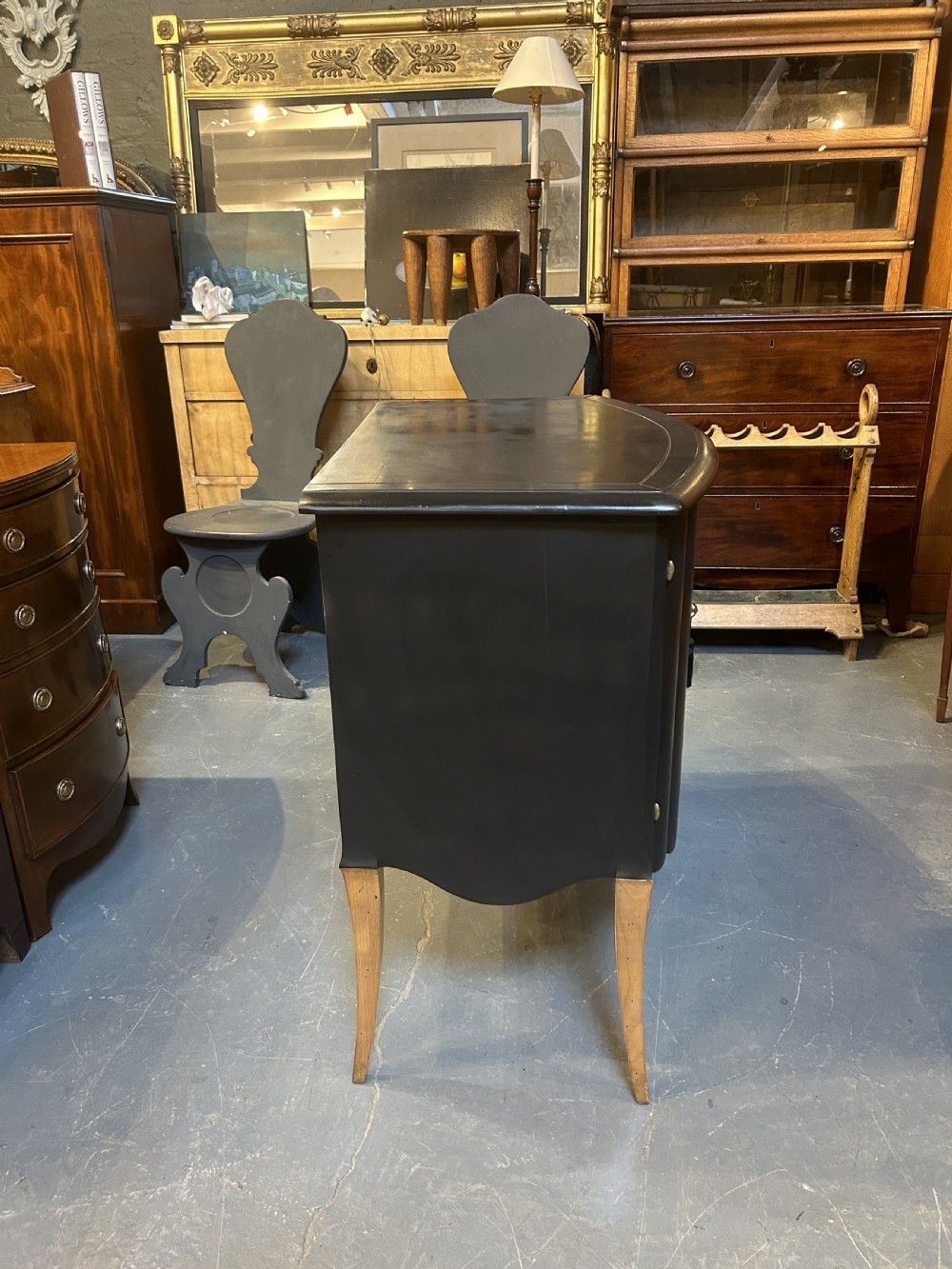 A French Art Deco black ebonised side cabinet with fluted doors, brass key hardware, and tapered light-coloured legs. View IV