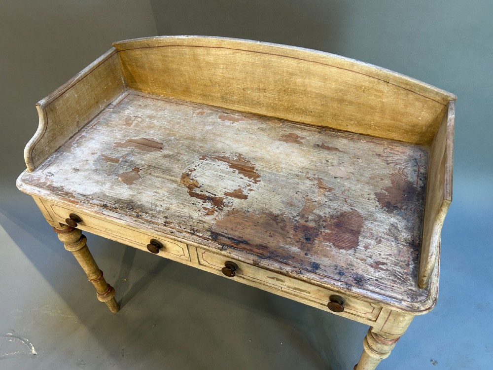 A Victorian cream painted writing table featuring a curved gallery backboard, two drawers with wooden turned knobs, and turned legs. View III