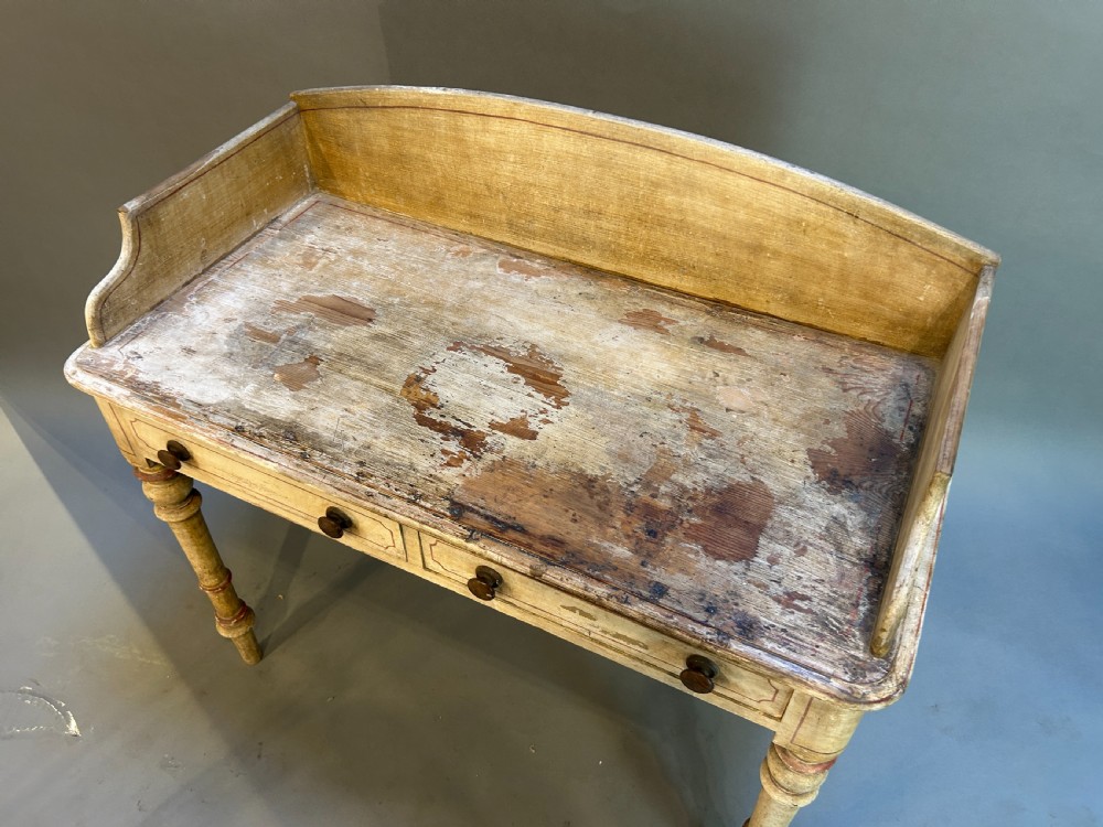 A Victorian cream painted writing table featuring a curved gallery backboard, two drawers with wooden turned knobs, and turned legs. View V