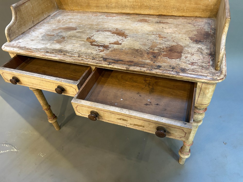 A Victorian cream painted writing table featuring a curved gallery backboard, two drawers with wooden turned knobs, and turned legs. View VI
