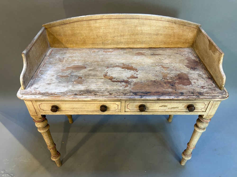 A Victorian cream painted writing table featuring a curved gallery backboard, two drawers with wooden turned knobs, and turned legs. View VIII
