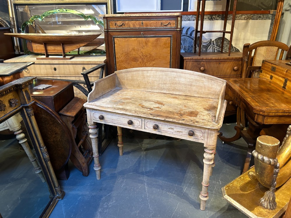 A Victorian cream painted writing table featuring a curved gallery backboard, two drawers with wooden turned knobs, and turned legs. View XI