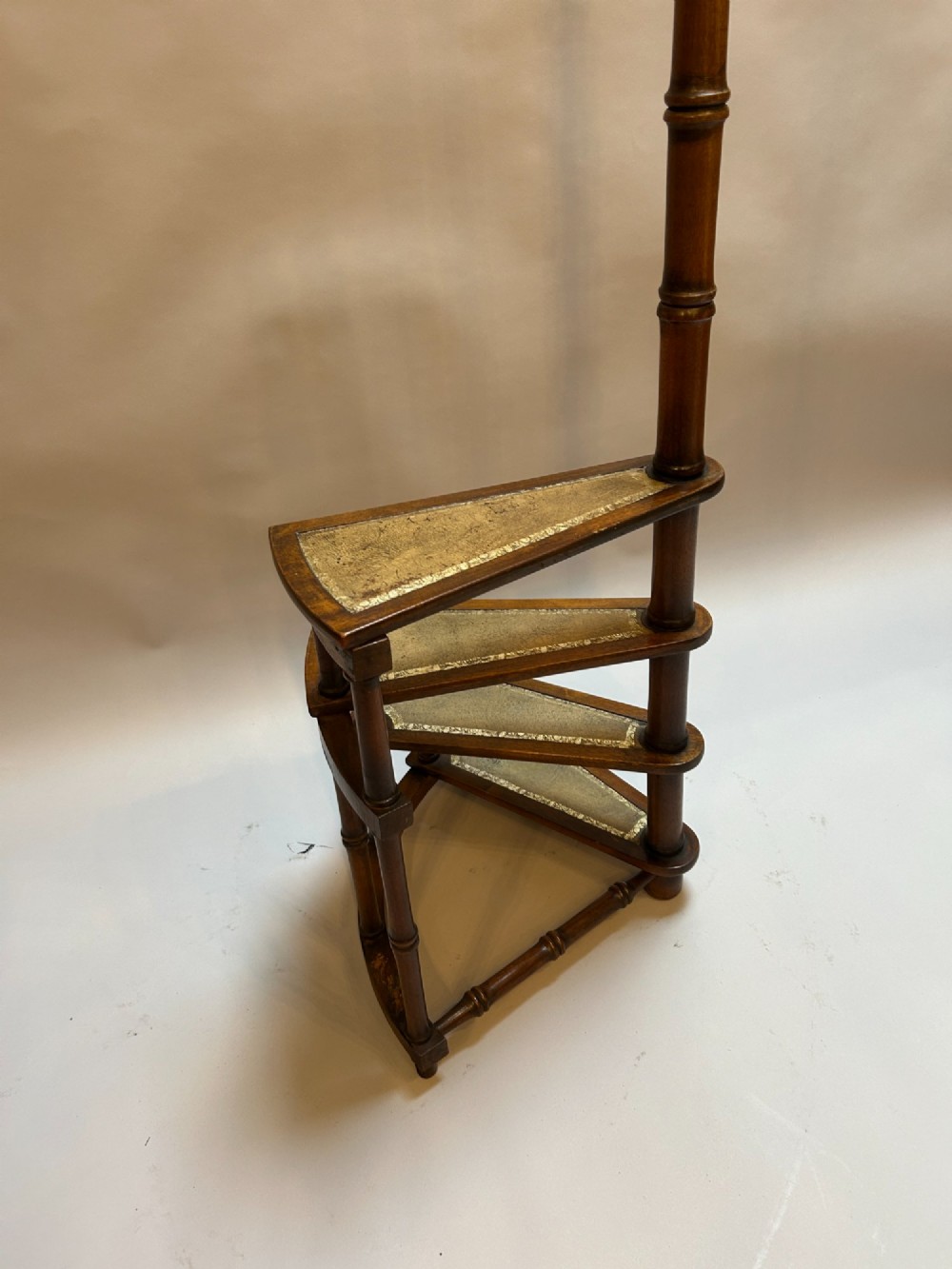 A set of spiral mahogany library steps featuring leather-lined treads and a tall central handrail post styled with faux-bamboo turnings and a brass finial. View VI
