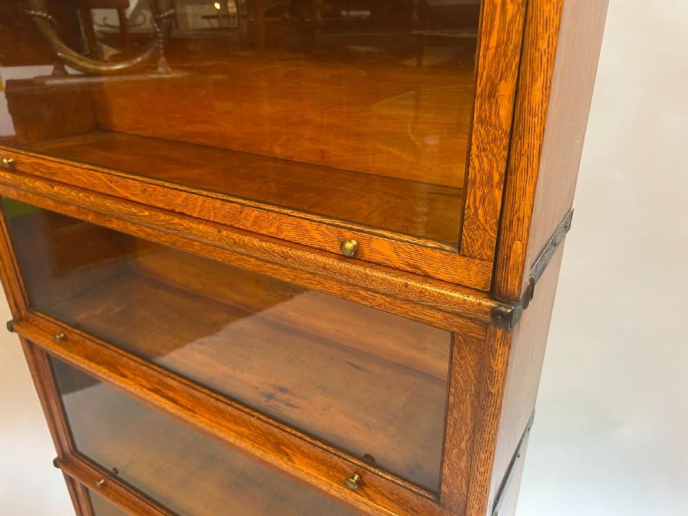 A five-tier oak Globe Wernicke stacking bookcase featuring glazed lift-and-slide doors, brass knobs, and side metal bands. View II