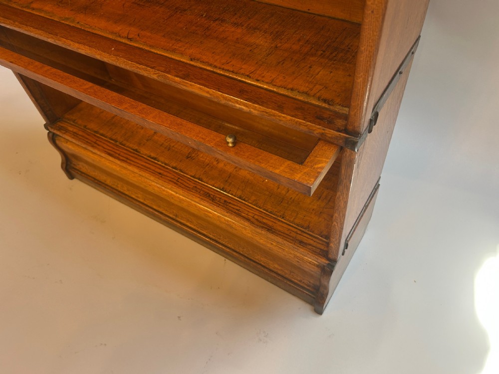 A five-tier oak Globe Wernicke stacking bookcase featuring glazed lift-and-slide doors, brass knobs, and side metal bands. View V