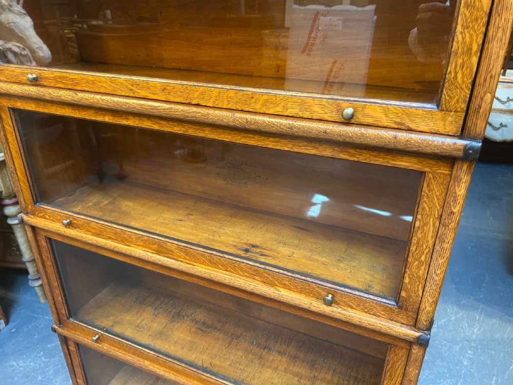 A five-tier oak Globe Wernicke stacking bookcase featuring glazed lift-and-slide doors, brass knobs, and side metal bands. View XI