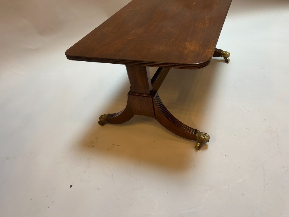 A rectangular George IV mahogany coffee table featuring reeded sweeping legs with brass lion paw castors. View IV