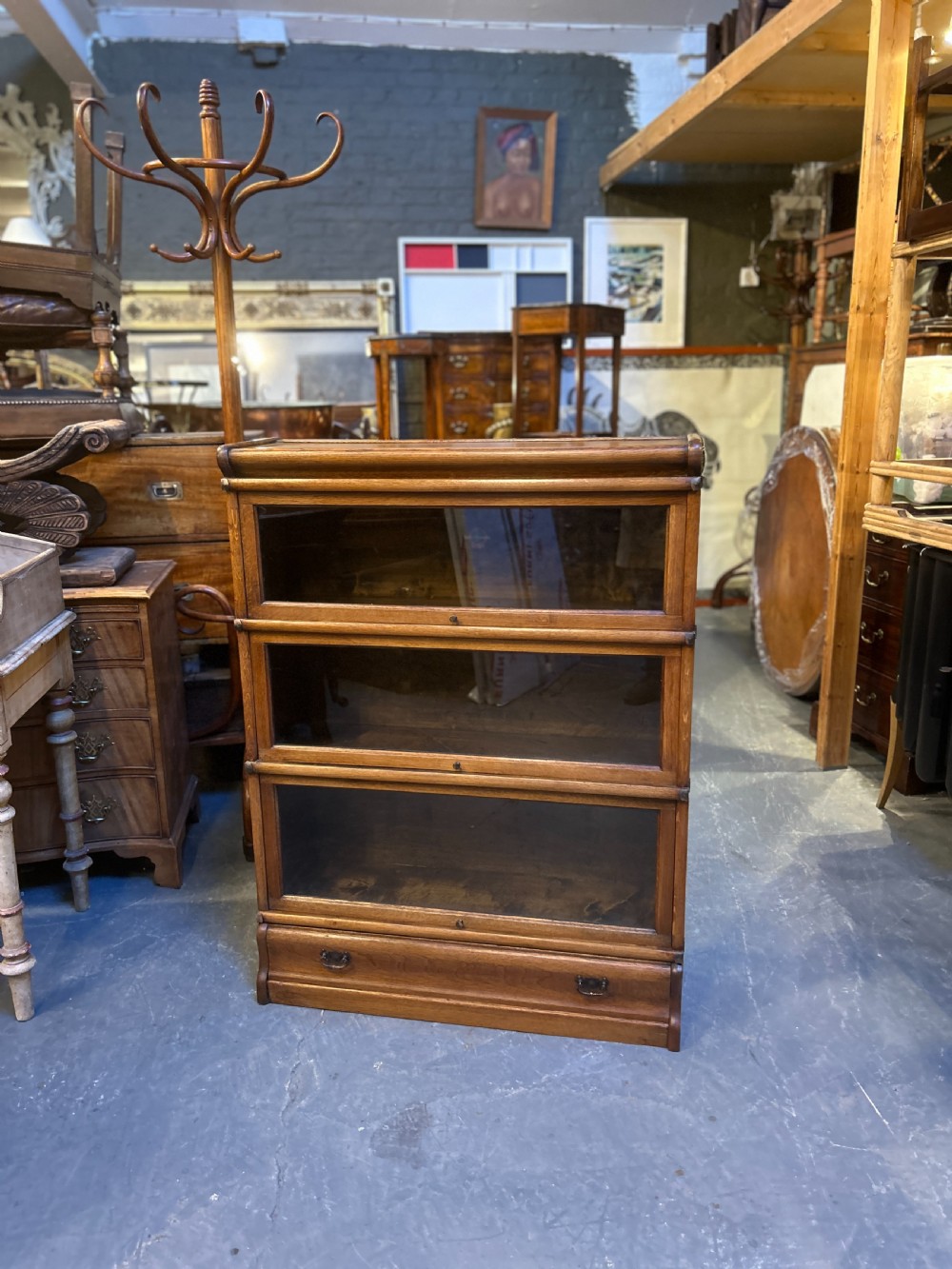 A three-tier antique oak Globe Wernicke stacking bookcase featuring glazed lift-up doors and a base drawer. View IX
